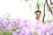 Girl bride in wedding dress with elegant hairstyle in Orychophragmus violaceus flower field