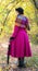 Girl in a bright crimson coat walking in forest sunny autumn day