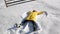 Girl in Bringh Yellow Jacket is Lying on the Ground and Making Snow Angel Having Fun During a Day Outside. Joyous Woman