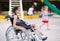 A girl with a broken leg sits in a wheelchair in front of the playground