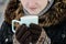 Girl in the brown gloves holding a blue mug of tea, part of the face, close-up