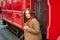 Girl brown hair in coat sit running Board red tram