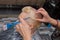 A girl with a brush in her hands in the process of dyeing the hair of an adult client, at work in a barbershop or salon