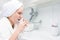 Girl brushes her teeth standing in front of a tap with water