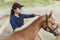 Girl Brushing Blonde Mane Of Her Flaxen Horse Outside The Stable During Daytime