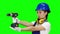 Girl builder holds a drill in his hands and looks around. Green screen. Close up