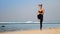 Girl with buns stands in yoga pose standing knee to chest