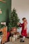 Girl burgundy dress decorates Christmas rustic room