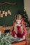 Girl burgundy dress decorates Christmas rustic room