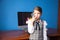 girl in a business suit stands at the computer and talks on the phone