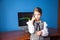 Girl in a business suit stands at the computer and talks on the phone