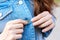 Girl buttoning a blue denim shirt. Closeup