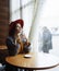 Girl in a cafe with a cup of coffee and a hat.portrait of sensual young girl wearing floppy hat and blouse with bow. Beautiful