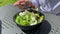 A girl in cafe on a summer terrace, near green grass eats a healthy green salad with cheese from disposable dishes in