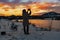 A girl with a camera shoots a colorful evening sunset on a cloudy sky from a height , the silhouette of the photographer in the da