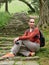 The girl with the camera sits on the vintage steps in a green park