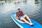 girl in a cap decided to try a new sport such as sap on the water and is trying to master.