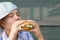 Girl in a cap, sitting at the table and eating fast food, Burger, close-up, there is a place for the inscription