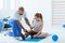 Girl after car accident with orthosis on the leg exercises on blue mat in the company of physiotherapist