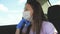 A girl in a car wearing a medical mask and blue gloves to prevent the spread of COVID-19. Riding a woman wearing a