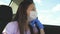 A girl in a car wearing a medical mask and blue gloves to prevent the spread of COVID-19. Riding a woman wearing a