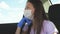 A girl in a car wearing a medical mask and blue gloves to prevent the spread of COVID-19. Riding a woman wearing a