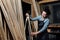 Girl carpenter with a tape measure on a background of wooden pieces in workshop.