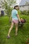 Girl carries on a wheelbarrow vegetables from garden