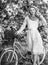 girl carry flowers in retro bicycle. spring beautiful woman in dress. girl vintage bike. blooming sakura tree. summer