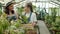 Girl carrying plants in greenhouse then talking to mother working together