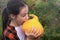 Girl of Caucasian ethnicity holds a Golden Pear pumpkin in her hands with her mouth wide open, wants to take a bite