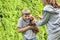 The girl caught the chicken and gives it to her younger brother in his hands