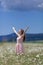 Girl in chamomile field with arms raised