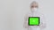 A girl in chemical protection picks up a digital tablet with a greenscreen. A medical woman in a disposable protective