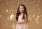 Girl child is in christmas lights, yellow background, pink dress