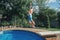 Girl child diving jumping in water on home backyard pool. Funny cute kid enjoying and having fun in swimming pool on summer day.