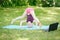 Girl child doing sport workout outdoor online. Video yoga stretching on Internet in park. Kid learning fitness gymnastics on