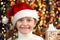 Girl child dressed in santa hat with christmas gifts on dark illuminated background, happy new year and winter celebration concept