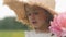 Girl child four years old stands in a field in a straw hat in a field