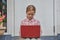 The girl child with a laptop is sitting on the porch of the house during a lesson on a remote photo without a filter