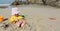 Girl child playing on the beach buries herself in the sand