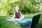 Girl child practicing yoga outdoor online. Video sport workout on Internet. Kid learning fitness training with laptop. A new