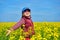 Girl child in rapeseed field with bright yellow flowers, spring landscape