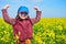 Girl child in rapeseed field with bright yellow flowers, spring landscape