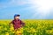 Girl child in rapeseed field with bright yellow flowers, spring landscape