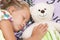 The girl child is sleeping with teddy bear.