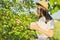 Girl child tearing berries in mug of mulberry tree, summer sunny day background