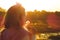 girl child in the twilight light of the setting sun, holding a white fluffy dandelion, glare of sun rays   .