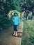 Girl child walking on street road under rain with rainbow umbrella