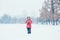 Girl child in warm clothes red pink jacket playing with snow having fun during cold winter snowy